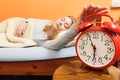 Woman waking up turning off alarm clock in morning Royalty Free Stock Photo