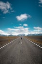 Woman walk alone in the Iceland, the road is empty.