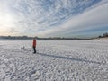 woman with winter coat walk the dog on frozen lake with thick snow in winter Royalty Free Stock Photo