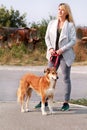 Woman in walk with his Shetland sheepdog dog on leash. Dog walker standing, posing in front of camera. Royalty Free Stock Photo