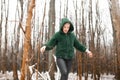 Woman walk in winter forest among bare trees looking down. Person in warm outfit from eco fur jacket relax in snow park. Royalty Free Stock Photo