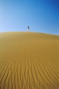 Woman walking across desert sand dune Royalty Free Stock Photo