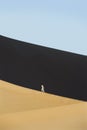 Woman walking across desert sand dunes Royalty Free Stock Photo
