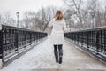 Woman walking across ornate iron bridge in city park in winter w Royalty Free Stock Photo