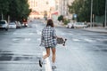 Woman walking across empty city road with skateboard in hand early in morning Royalty Free Stock Photo
