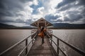 Woman walking across wooden bridge across lake on cloudy day long exposure Royalty Free Stock Photo