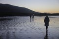 Woman walking alone on the beach before sunset