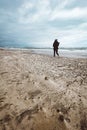 Woman walking alone on the beach on windy stormy day