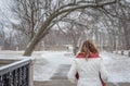 Woman walking in park in winter with fresh snow falling