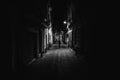 Woman walking alone in the street late at night.Narrow dark alley,unsafe female silhouette.Empty streets.Woman pedestrian alone. Royalty Free Stock Photo