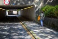 A woman walking alone about to walk under a subway or underground walkway