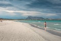 Woman walking along San Teodoro sand beach with turquoise sea water and mountains of island Tavolara in Sardinia Italy Royalty Free Stock Photo