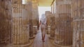 Woman is walking amongst world's oldest known stone columns at Djoser's step pyramid complex.