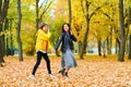 Woman walking with autumn leaves in city park, outdoor portrait