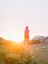 Woman walking away in the sunlight on a hill top footpath at Pembrokeshire Coast Path at sunset in Martins Haven - Pembrokeshire,