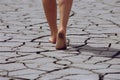 Woman walking barefoot across cracked earth