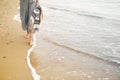 Woman walking barefoot on beach, close up view of legs and waves. Young girl relaxing on sandy beach near sea, walking with bag in Royalty Free Stock Photo