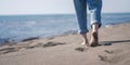 Woman walking barefoot on the sandy sea beach. No face, legs in jeans close-up Royalty Free Stock Photo