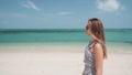 Woman walking on beach flicks hair on sunny day