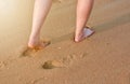 People`s feet walking along the fine sand beach.