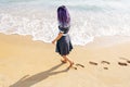 Woman walking on beach leaving footprints on sand. Royalty Free Stock Photo