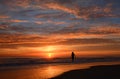 Woman walking on the beach at sunrise.