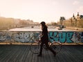 Woman walking bicycle across Pont des Arts at sunset