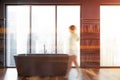 Woman walking in black bathroom with tub Royalty Free Stock Photo