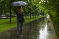 Woman walking with black umbrella under the rain in a park Royalty Free Stock Photo