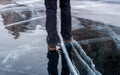 Woman walking on blue cracked ice of frozen lake Baikal.