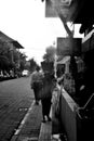 Woman is walking and carrying a basket on her head on the street of Ubud in Bali. Black and white photography from Indonesia Royalty Free Stock Photo