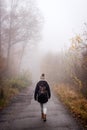 Woman walking on country road in fog at autumn morning Royalty Free Stock Photo