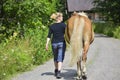 Woman walking with horse on country road