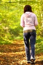 Woman walking cross country trail in autumn forest Royalty Free Stock Photo