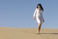 Woman walking in the desert wearing white clothes