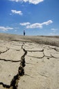 Woman walking on desolate cracked earth landscape