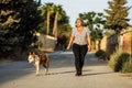 Woman walking a dog on an unpaved street