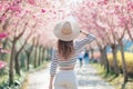 A woman is walking down a path lined with beautiful pink flowers, taking in the serene and picturesque surroundings Royalty Free Stock Photo