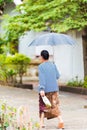 Woman walking down the street under an umbrella in Louangphabang, Laos. Vertical.