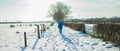 Woman walking in dutch rural winter landscape.