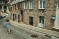 Woman walking in front of old houses in a cobblestone alley