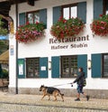 Woman walking German Shepard in front of restaurant in Oberammergau Bavaria Germany