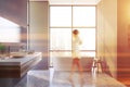 Woman walking in gray bathroom with sink and tub Royalty Free Stock Photo