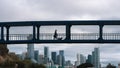 Woman walking her dog on a pedestrian overpass on a cloudy day; San Francisco financial district skyline visible in the background Royalty Free Stock Photo