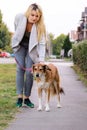 Woman walking with his Shetland sheepdog dog on leash, posing in front of camera. Portrait of lady, owner and Rough collie dog. Royalty Free Stock Photo