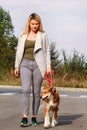 Woman walking with his Shetland sheepdog dog on leash, posing in front of camera. Portrait of lady, owner and Rough collie dog. Royalty Free Stock Photo