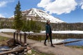 Woman walking Lake Trail surrounded by Mountains and Trees in Amercian Landscape.