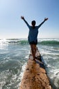 Woman walking out onto break wall with waves of ocean in front