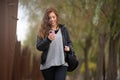 Woman walking in the park looking at her mobile phone in autumn Royalty Free Stock Photo