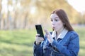 Woman walking through the park looking at her smartphone in surprise Royalty Free Stock Photo